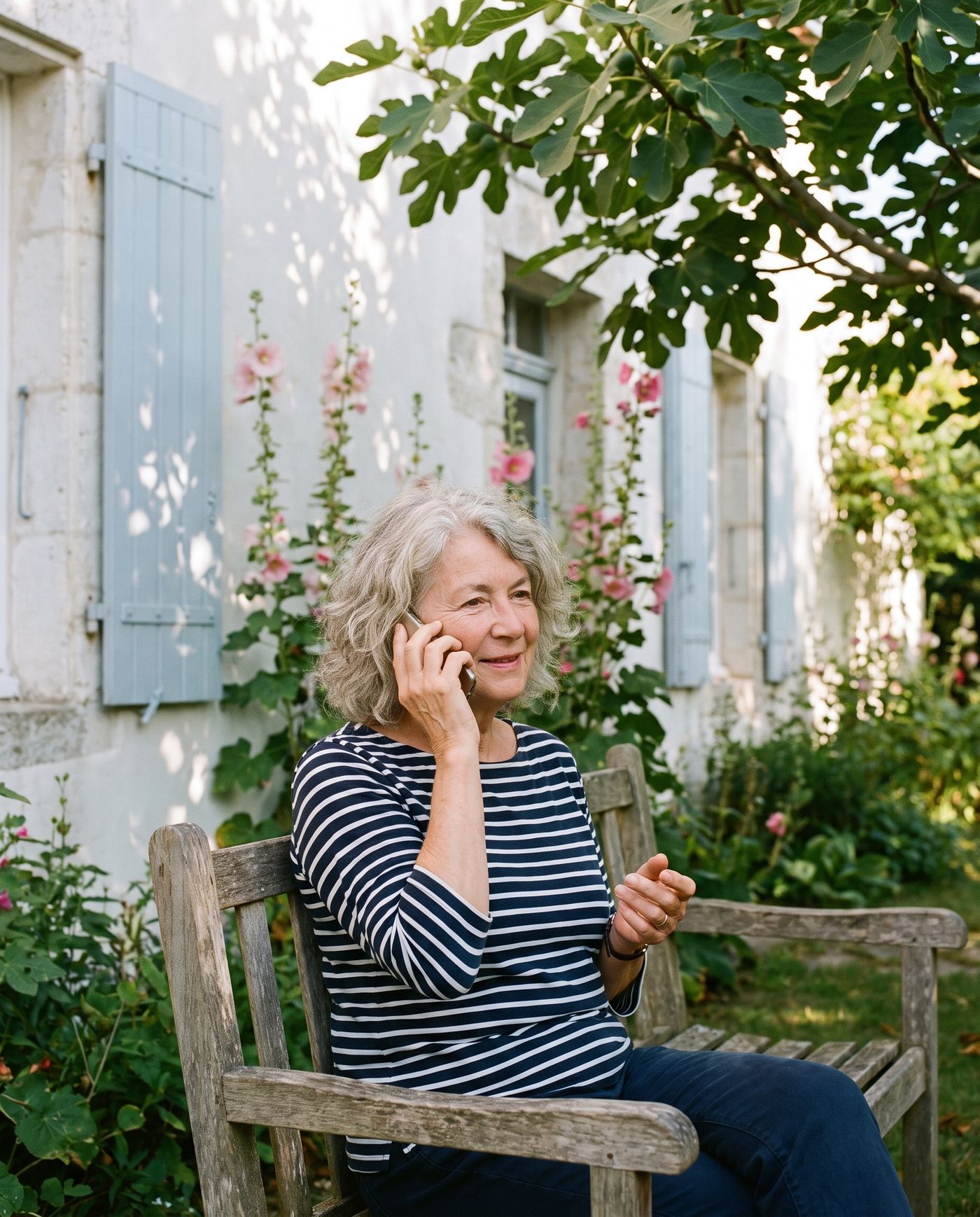 Une femme au téléphone sur un banc de jardin, souriante et détendue